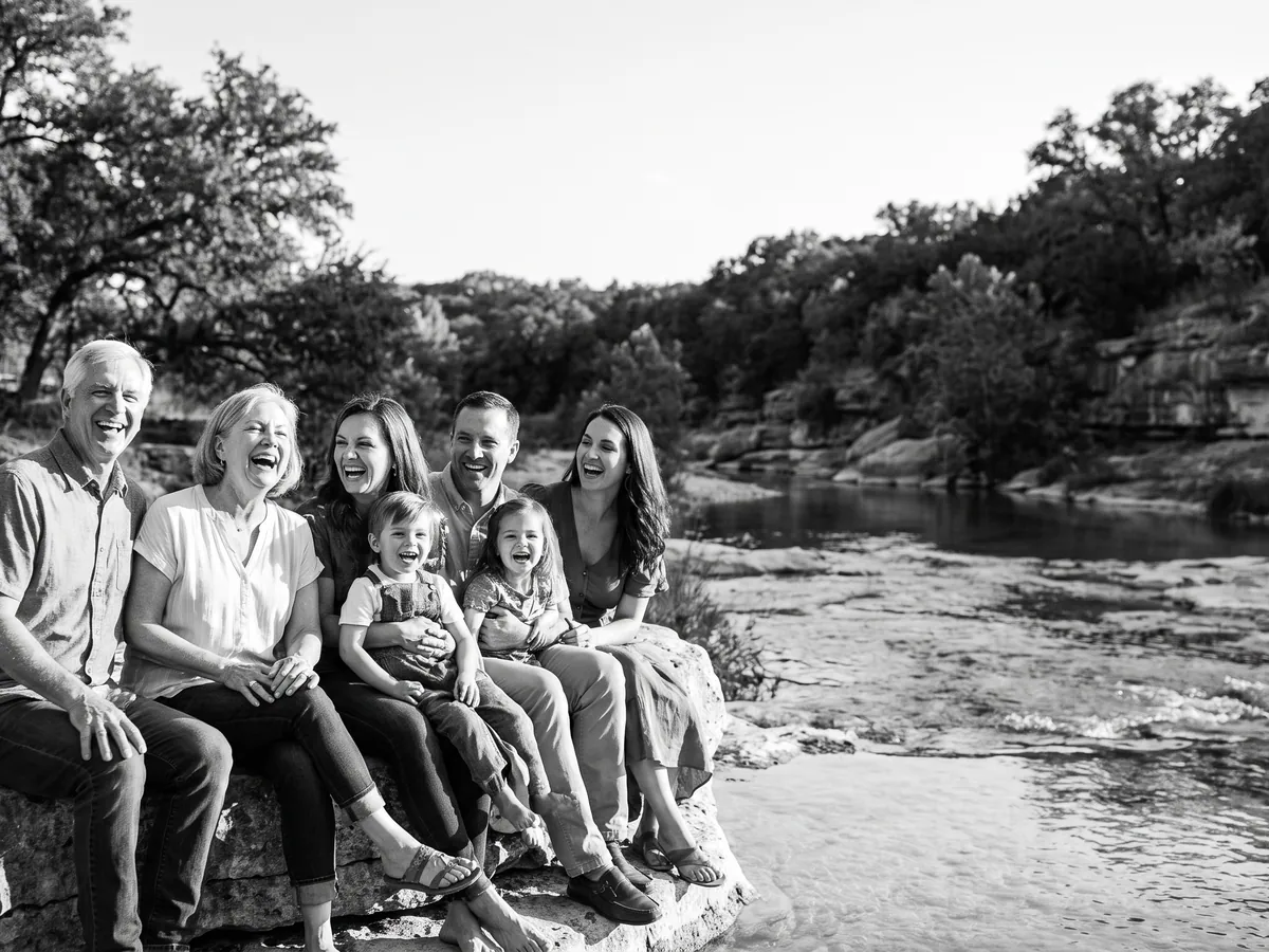 Una familia sonriente sobre una roca de piedra caliza junto a un río de Hill Country
